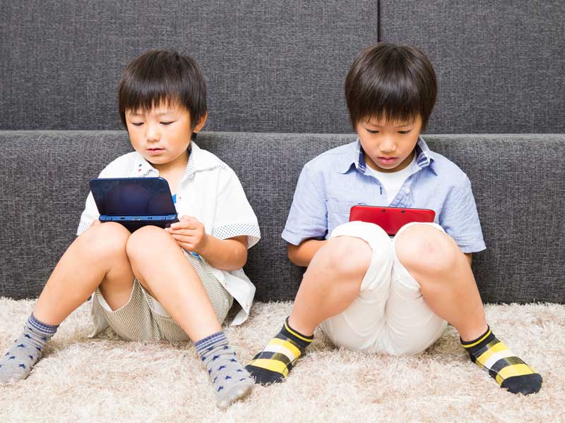 ゲーム機で遊んでいる子供達
