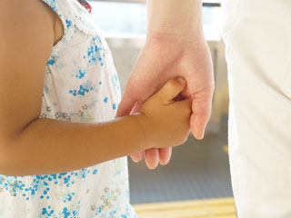子供の手を握る親の手
