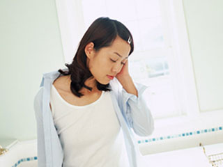 手で頭を押さえる女性