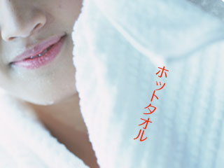 蒸しタオルを顔に当てる女性