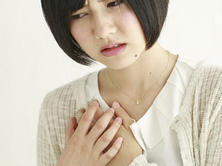 胸を両手で押さえる女性