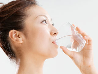 コップで白湯を飲む女性
