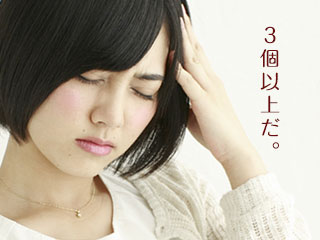 頭に手を当てて顔をしかめる女性