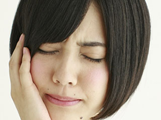 手でこめかみを押さえて痛がる女性