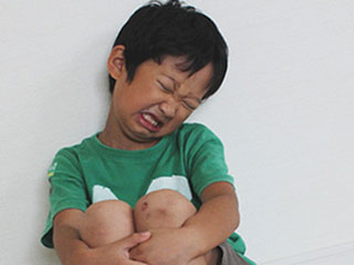 膝を抱えて痛がる子供