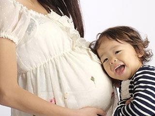 妊婦のお腹に耳を当てる子供