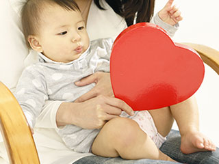 赤ちゃんを膝に座わらせる母親