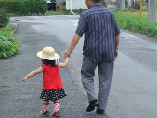 孫の手を引いて散歩する祖父