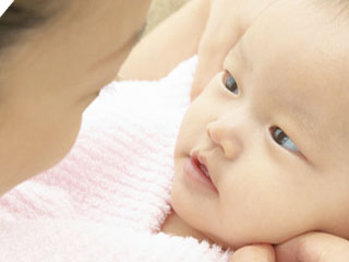 赤ちゃんの顔を覗き込む母親