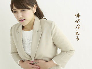 お腹を押さえながら不快な表情の女性