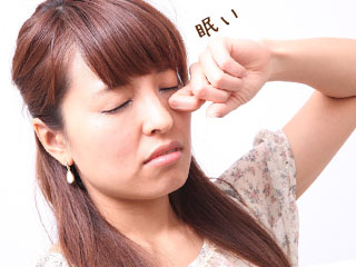 眠そうに目をこする女性