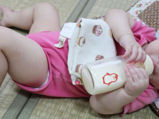 寝そべりながら哺乳瓶からミルクを飲む赤ちゃん