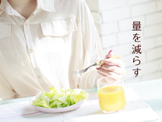 ジュースとサラダを前にフォークを持つ女性