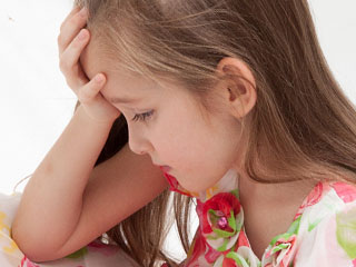 おでこを手で押さえながら痛そうな子供