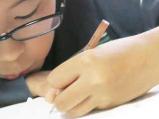 机に顔を近づけて勉強する子供