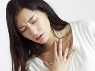 胸に手を当てて苦しそうな女性