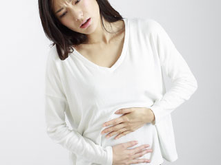 お腹を押さえて痛がる女性