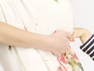 妊婦のお腹に触る子供の手