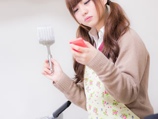 料理をしながらスマホチェックをするお母さん