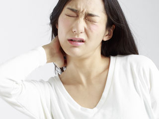 肩を押さえて痛がる女性