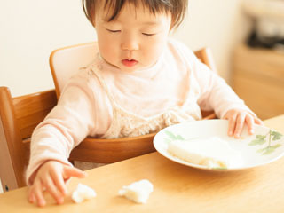 こぼれたご飯を摘む赤ちゃん