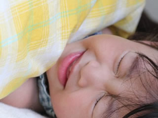 黄色い布団で休む熱が出て具合が悪い子供