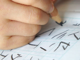 鉛筆で字を書く子供の手