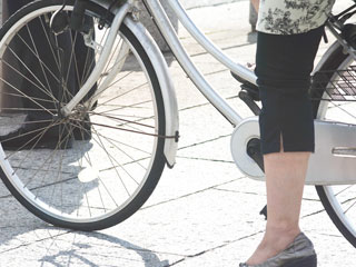 歩道で止まる女性が乗った自転車
