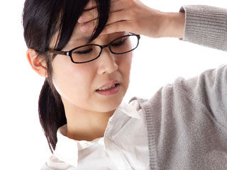 額に手をやって痛そうな女性