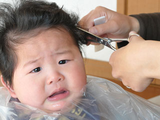 赤ちゃんのサイドの頭髪を切る