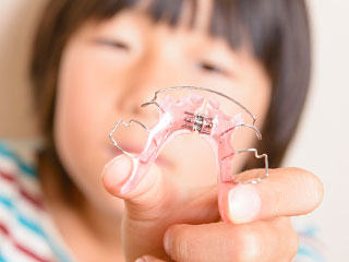 矯正器具を見せる子供