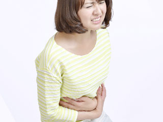 苦しそうにお腹を押さえる女性