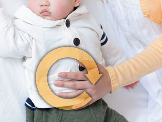 赤ちゃんのお腹の上に掌を置く母親