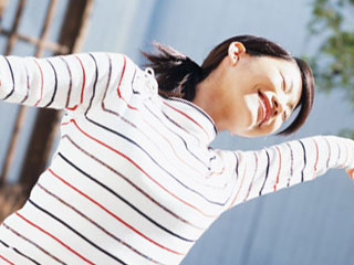 朝、手を広げて背伸びする女性