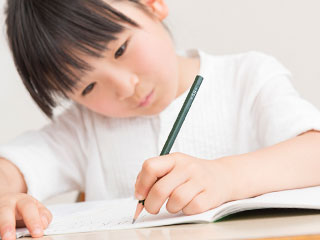 鉛筆でノートに字を書く児童
