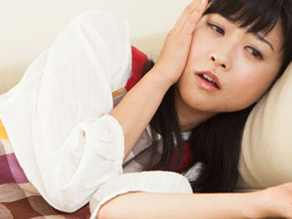 横になって顔を触る女性