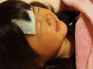 額にシートを張って寝込む子供