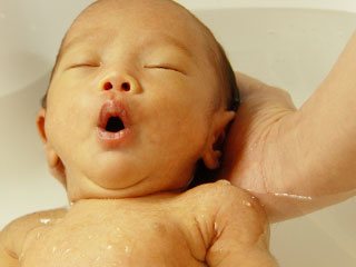 赤ちゃんの頭を支えて沐浴させる