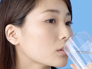 コップで水を飲む女性