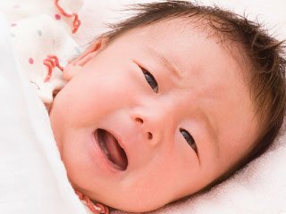 布団の中で目を開けている赤ちゃん