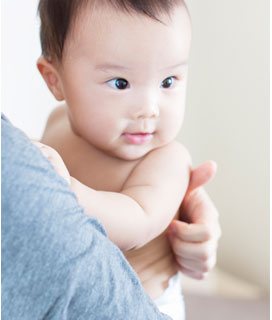 赤ちゃんを抱いて背中に手を当てる親