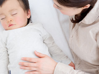 赤ちゃんのお腹に掌を置く母親