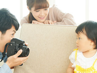 赤ちゃんの写真を撮る血父親と見守る母親