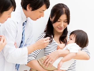 母親が抱いた乳児を診察する医者