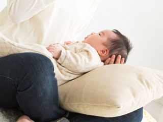 母親の膝の上に寝かされた赤ちゃん