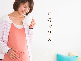 カップで飲み物を口にしてくつろぐ妊婦