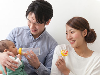 育児を手伝う夫の横で笑顔の女性