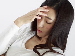 額に手をやって考える女性