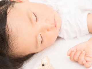片方の耳を布団に付けて寝る赤ちゃん