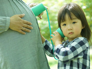 妊婦のお腹に耳を澄ます子供